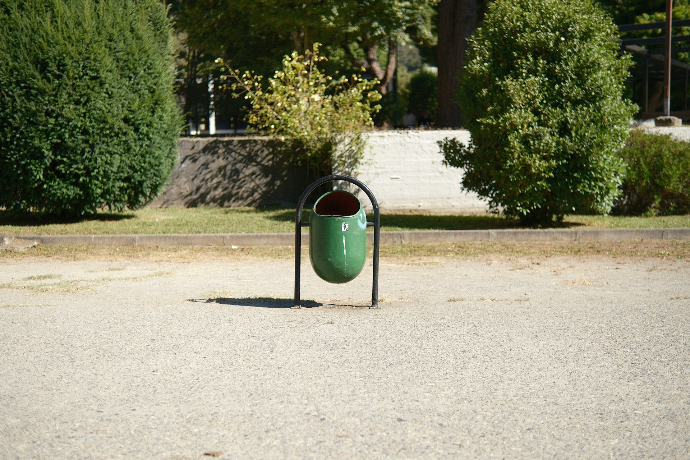 A trash can sitting in the middle of a parking lot